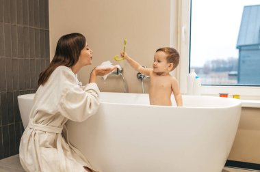 Anne banyoda bebeğiyle oynuyor.