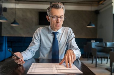 Bir kafede oturan göz giysili zarif bir adam.