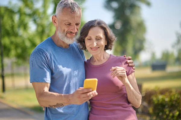 Una pareja feliz en el parque sintiéndose bien y haciendo selfie — Foto de Stock