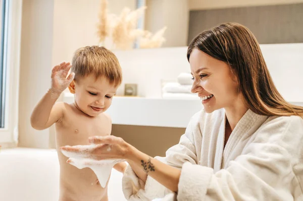 Fröhliche junge Mutter spielt mit ihrem männlichen Kind — Stockfoto