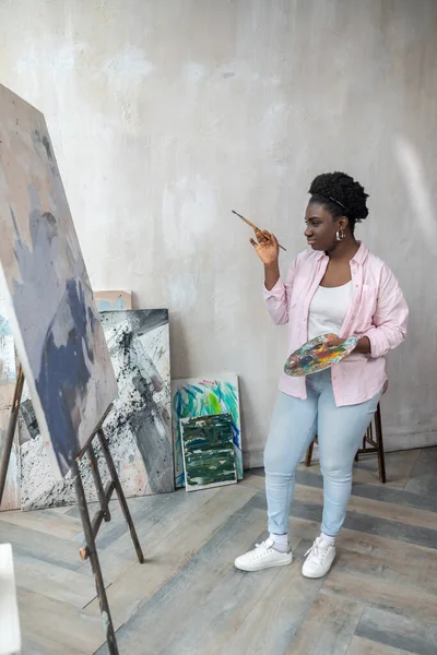 Contenuti artista africano in abiti rosa clooking occupato in studio — Foto Stock
