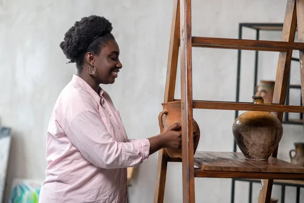 Gut aussehende Afrikanerin steht neben den Regalen mit Keramik — Stockfoto
