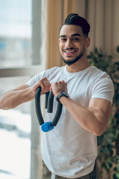 A man in a white tshirt exercising with expander — Stock Photo, Image