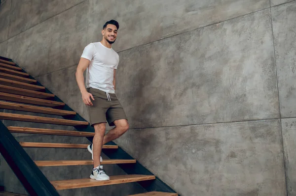 Молодой человек в футболке и шортах на лестнице дома — стоковое фото