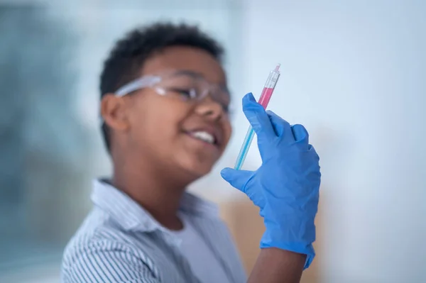 Un garçon souriant dans des lunettes de protection tenant une seringue à la main — Photo