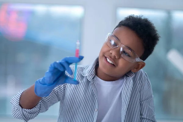 stock image A smiling boy in protective eyeglasses holding a syringe in hand