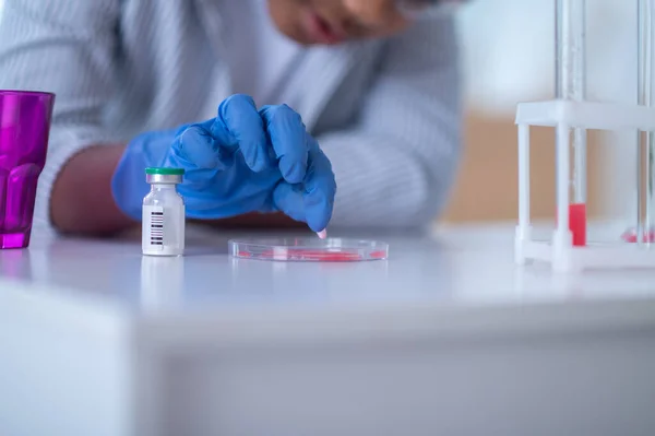 Un garçon en blouse de laboratoire travaillant avec des éprouvettes et regardant impliqué — Photo