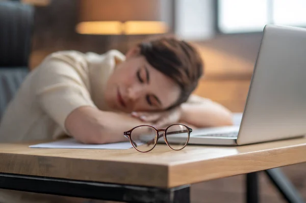 Ciemnowłosa kobieta drzemie przy laptopie po ciężkim dniu — Zdjęcie stockowe