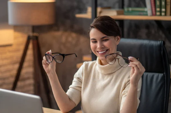 A young woman holding two pairs of eyeglasses and smiling — Stock Photo, Image