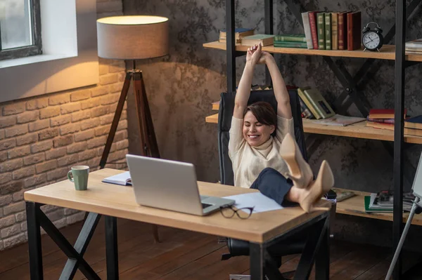 En ung kvinna som kopplar av på kontoret efter jobbet — Stockfoto
