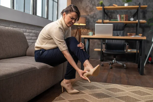 A woman taking off shoes on high heels after a long day — Stock Photo, Image