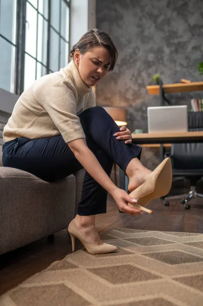 A woman taking off shoes on high heels after a long day — Stock Photo, Image