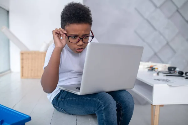 Seorang remaja yang lucu duduk di laptop dan melihat terlibat — Stok Foto