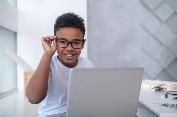 En söt tonåring sitter vid datorn och ser involverad — Stockfoto