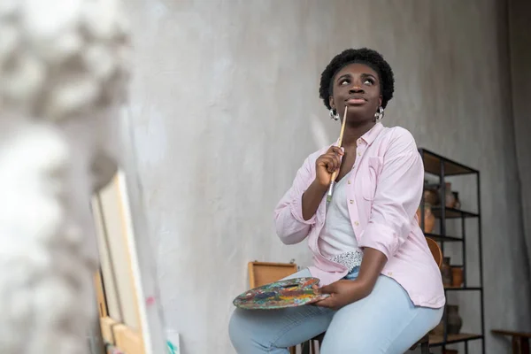 Contented african artist in pink clothes looking inspired — Stock Photo, Image