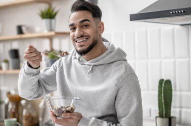 Genç bir adam sabahını evde kahve içerek geçiriyor.