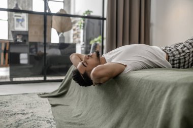 Yatakta uzanmış ve rahatlamış görünen bir adam.