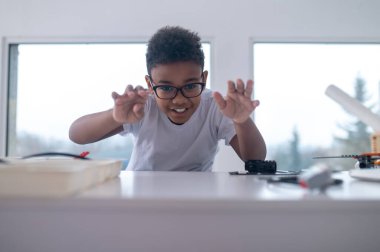 Masada yuvarlanan gözlüklü bir çocuk.