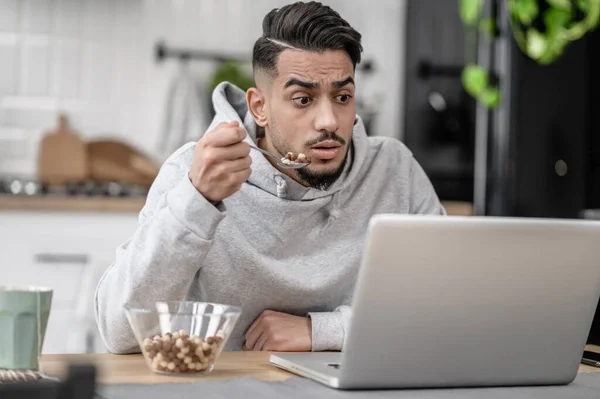 Un joven desayunando y viendo algo — Foto de Stock