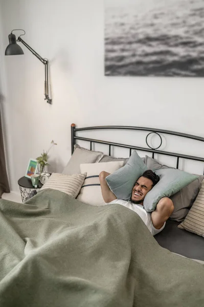 En ung man som känner sig sömnig och ligger i sängen — Stockfoto