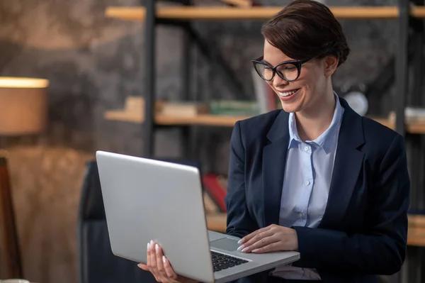 Elegante mujer morena con un portátil en las manos — Foto de Stock