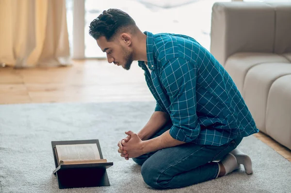 Genç Müslüman evde namaz kılıyor ve Kuran okuyor. — Stok fotoğraf