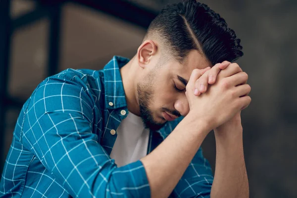 Joven hombre moreno sentado con una mirada infeliz —  Fotos de Stock