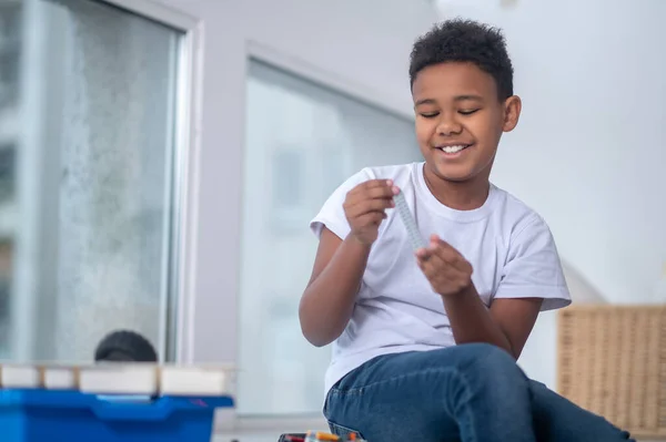Un chico de piel oscura jugando con un juguete cerca de la ventana — Foto de Stock