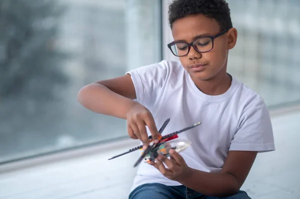 Un chico con gafas jugando con un helicóptero de juguete — Foto de Stock