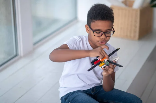 A boy in eyeglasses playing with a toy helicopter — 스톡 사진