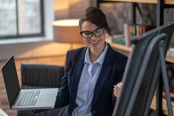 Elegante donkerharige vrouw presenteert iets aan online publiek — Stockfoto