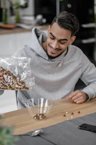 A smiling man in a grey hoodie making breakfast — Foto de Stock
