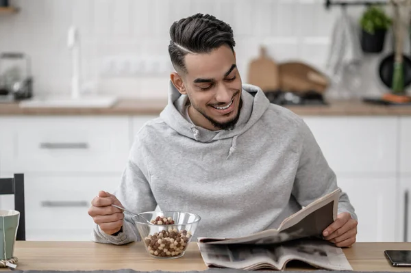 A young man having breakfast and reading a newspaper — Foto de Stock