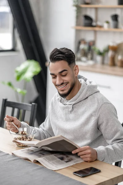 Um jovem tomando café da manhã e lendo um jornal — Fotografia de Stock