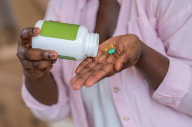 Genç Afrikalı kadın vitamin alıyor ve gülümsüyor.