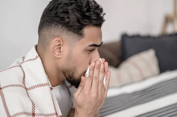 A dark-haired man having a flue and cleaning his nose — Foto de Stock