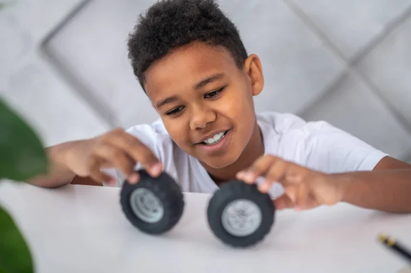 おもちゃの車輪で遊んでいる暗い肌の少年 — ストック写真