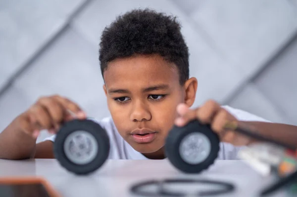 A dark-skinned boy playing with toy vehicle wheels — Photo