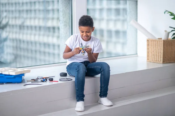 Afrikansk amerikansk pojke i vit tröja spelar och ser involverad — Stockfoto