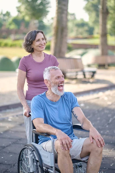 Uma mulher e um homem em uma cadeira de rodas sentindo-se feliz e sorrindo — Fotografia de Stock