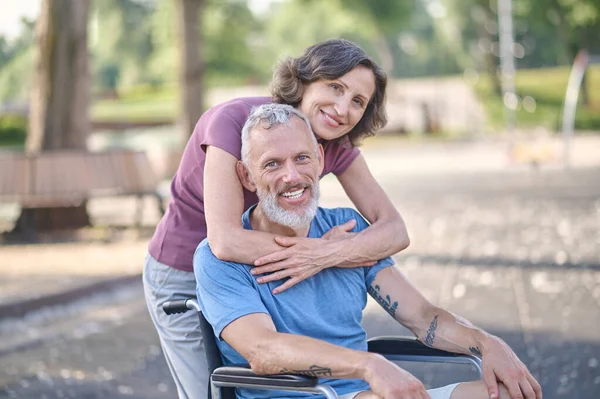 Μια γυναίκα και ένας άντρας σε αναπηρική καρέκλα αισθάνονται ευτυχισμένοι και χαμογελαστοί. — Φωτογραφία Αρχείου