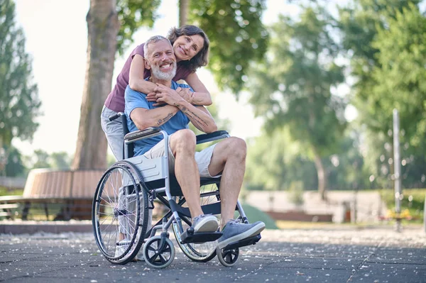 Una donna e un uomo su una sedia a rotelle si sentono felici e sorridenti — Foto Stock