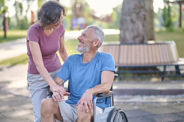 Un bărbat într-un scaun cu rotile și soția sa la o plimbare în parc — Fotografie, imagine de stoc