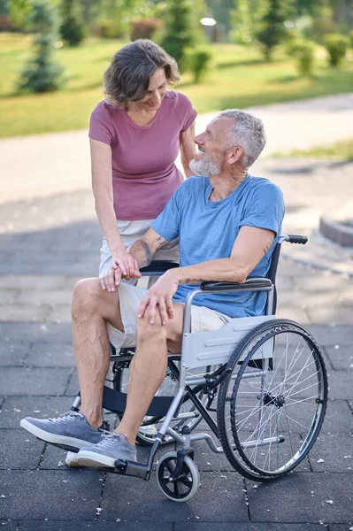 A man in a wheel chair and his wife on a walk in the park — Stock Photo, Image