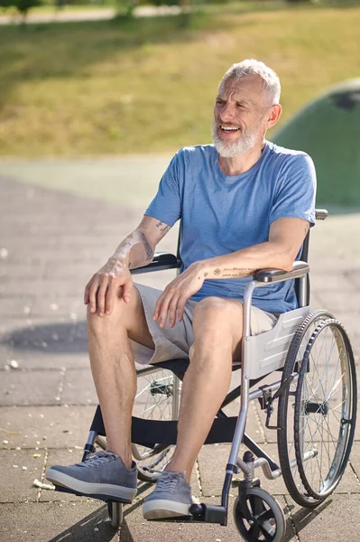 Um homem de cabelos grisalhos numa cadeira de rodas no parque — Fotografia de Stock