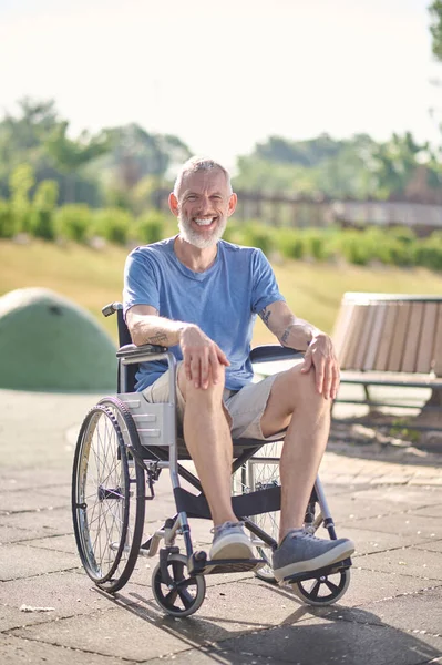 Parktaki tekerlekli sandalyede oturan gri saçlı bir adam. — Stok fotoğraf
