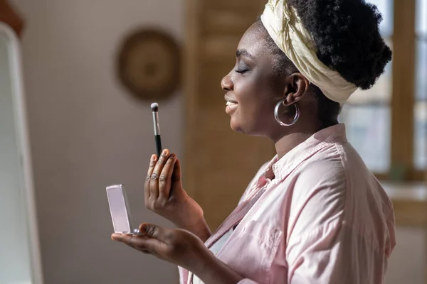 Nöjd afrikansk kvinna i lätta kläder håller pulver i händerna — Stockfoto
