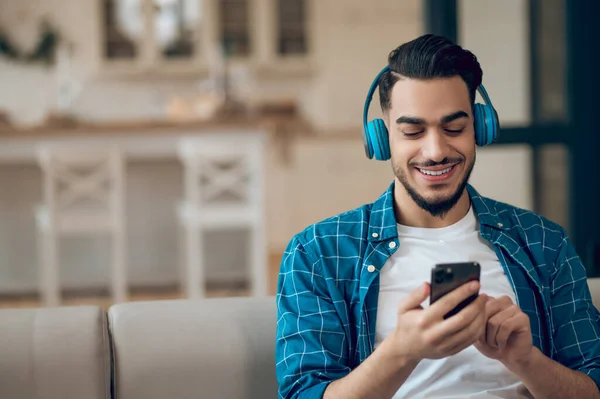 Junger Mann im blauen T-Shirt hört Musik und fühlt sich wohl — Stockfoto