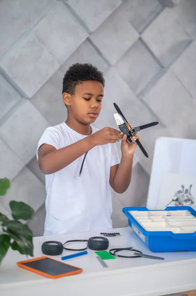 En söt tonåring ser upptagen medan montera leksak heicopter delar — Stockfoto
