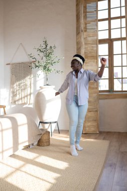 Açık renk elbiseli Afrikalı kadın evde vakit geçiriyor.